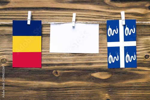 Hanging flags of Chad and Martinique attached to rope with clothes pins with copy space on white note paper on wooden background.Diplomatic relations between countries. photo