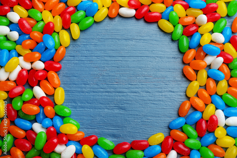 Frame made of colorful jelly beans on blue wooden background, flat lay. Space for text Frame made of colorful jelly beans on blue wooden background, flat lay. Space for text