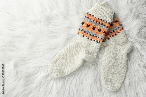 Knitted socks on white faux fur, flat lay. Space for text