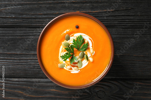 Delicious pumpkin soup in bowl on wooden table, top view