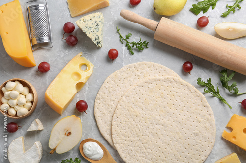 Flat lay composition with pizza crusts and fresh ingredients on marble table