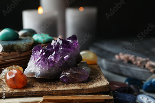 Many different gemstones and blurred candles on background photo