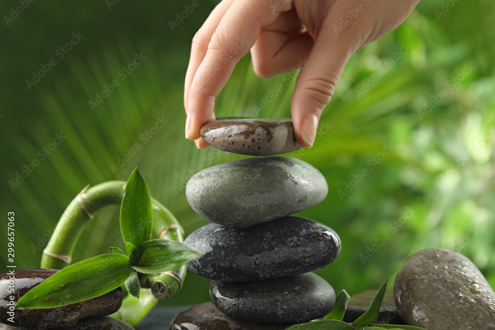 Woman stacking stones against blurred background, closeup. Zen concept - obrazy, fototapety, plakaty 