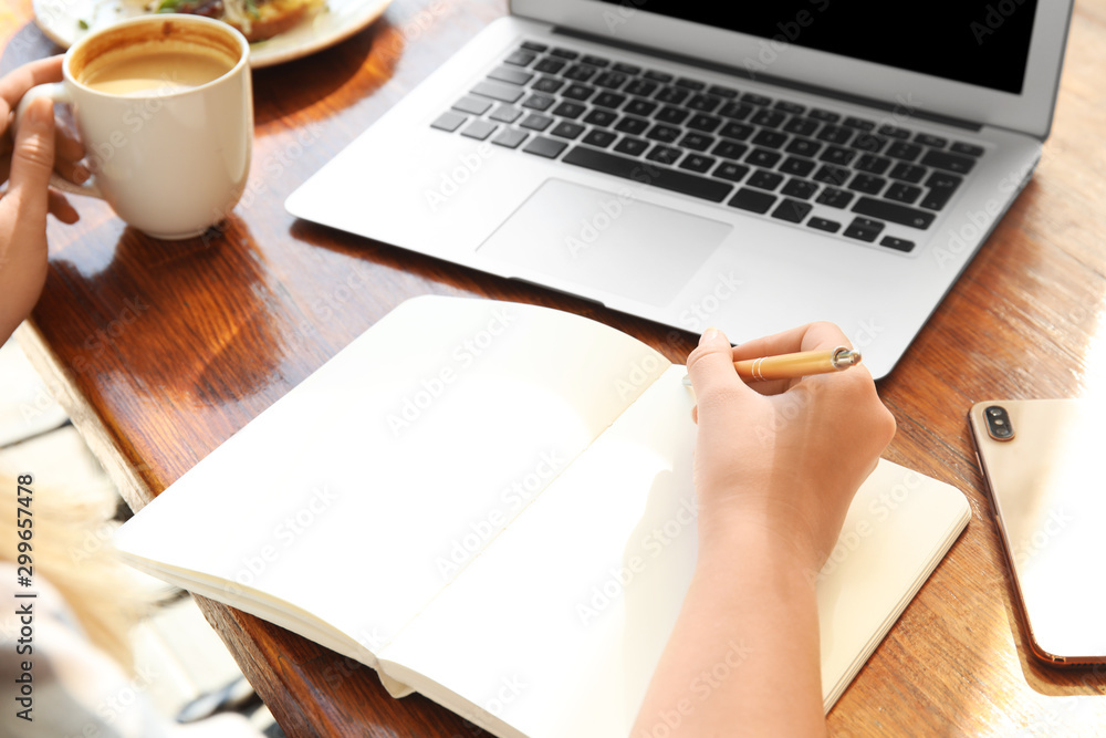 Woman writing blog content in notebook at table, closeup Woman writing blog content in notebook at table, closeup