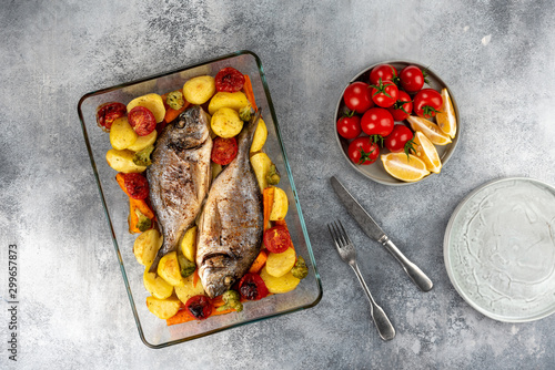 Baked dorado (dorada) fish on a plate, top view