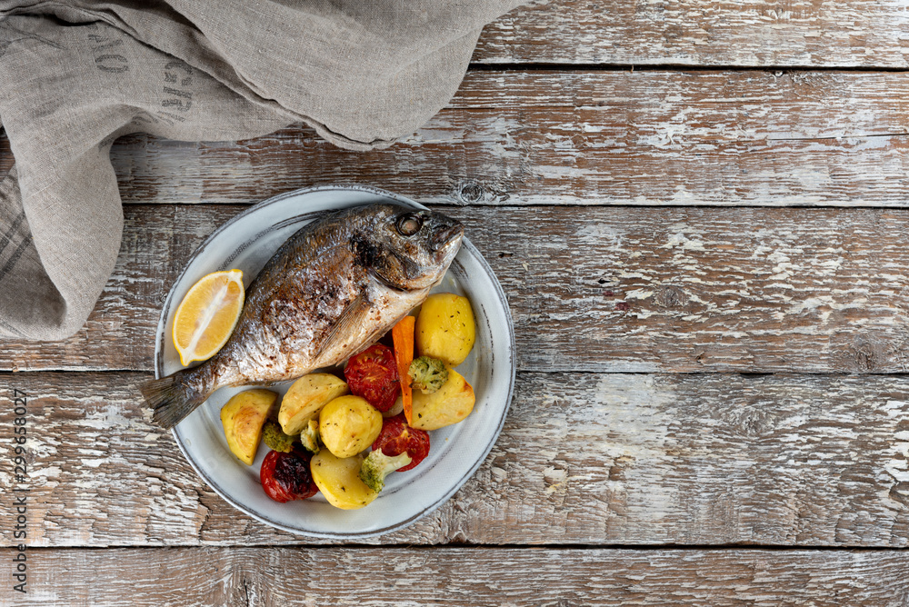 Baked dorado (dorada) fish on a plate, top view