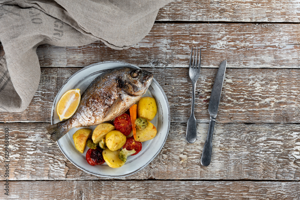 Baked dorado (dorada) fish on a plate, top view