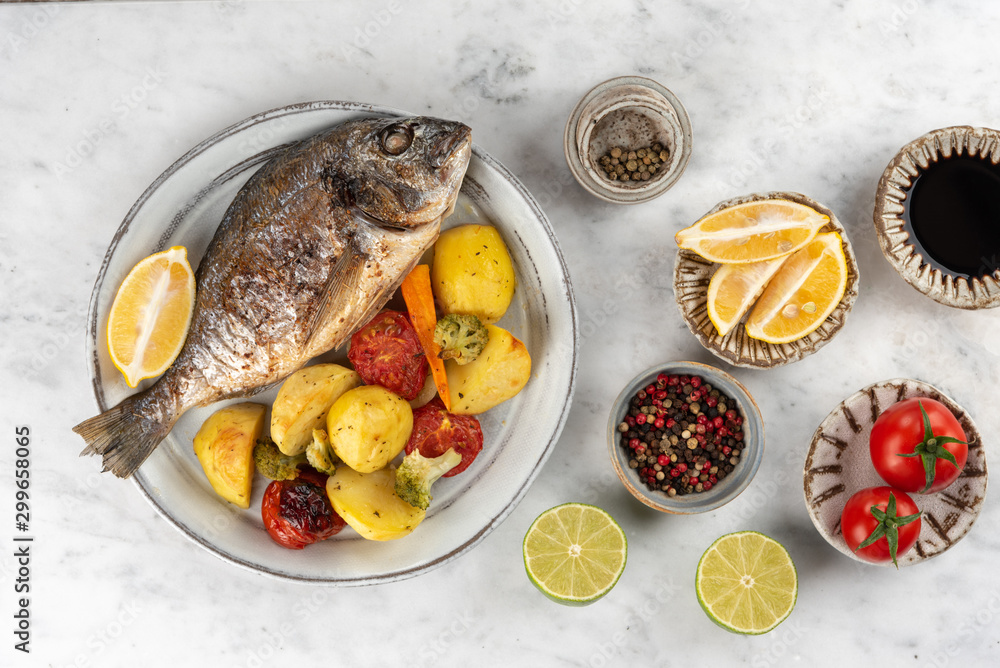 Baked dorado (dorada) fish on a plate, top view