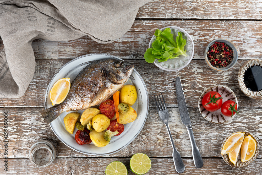 Baked dorado (dorada) fish on a plate, top view