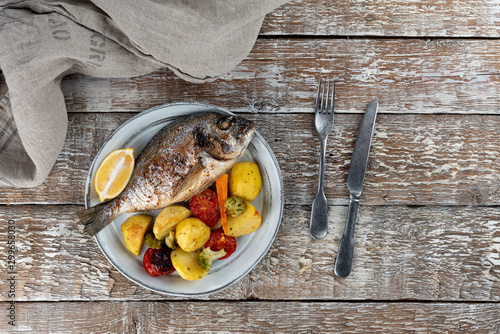 Obraz na płótnie Baked dorado (dorada) fish on a plate, top view w salonie