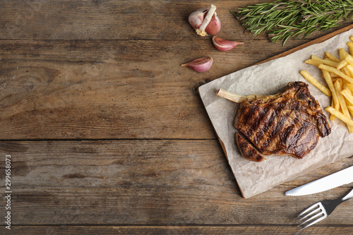 Flat lay composition with grilled beef steak on wooden table, space for text