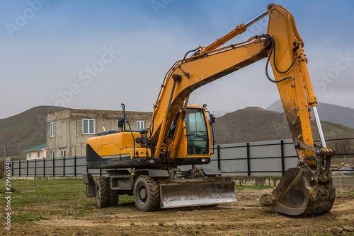 Yellow excavator at the construction of a cottage