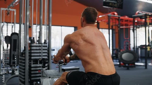 Strong shitless man using training machine in fitness club. Bodybuilding concept photo