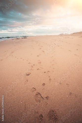 Beautiful seascape, a beach at sunset with footprint, close focus on print, and sunflare, exceptional tonality of color,warm and cyan