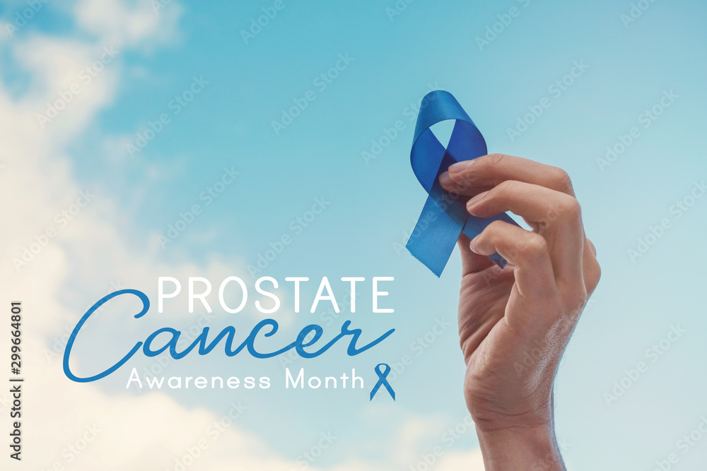Man Hands holding blue ribbon over blue sky, Prostate Cancer Awareness, November blue, Men health awareness - obrazy, fototapety, plakaty 
