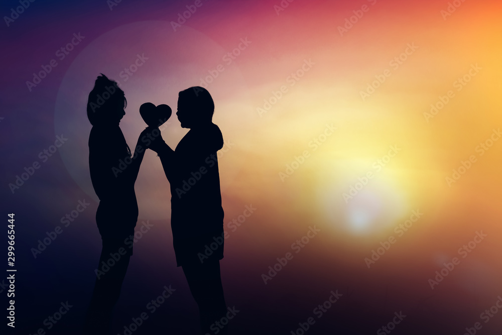 Silhouette at sunset two girl loving holding hand and heart in light.