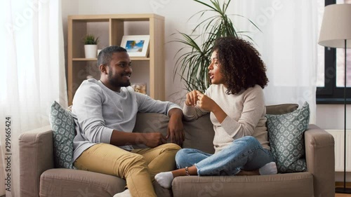 communication, relationships and people concept - happy couple sitting on sofa and talking at home