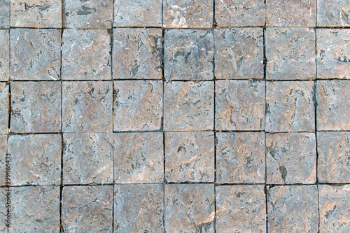 Granite cobblestoned pavement background. Fragment of a pavement along a street in Greece.