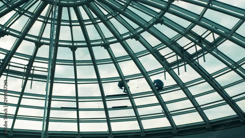 Workers washing the roof made of glass of a modern office building Workers washing the roof made of glass of a modern office building