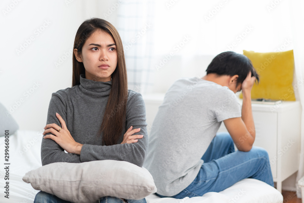 Lover couple relationship problems. Sad young wife sitting on the bed back to back from husband after argument. Lover couple relationship problems. Sad young wife sitting on the bed back to back from husband after argument.