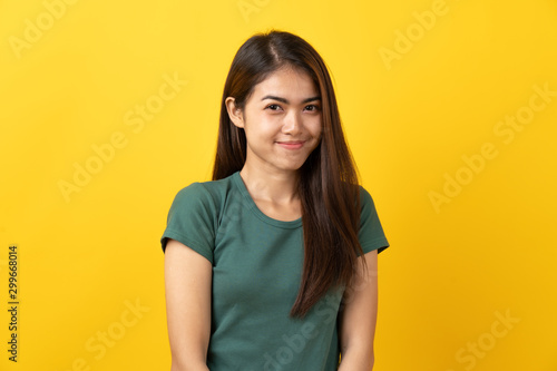 Shy asian young woman smiling facial expression on yellow background.