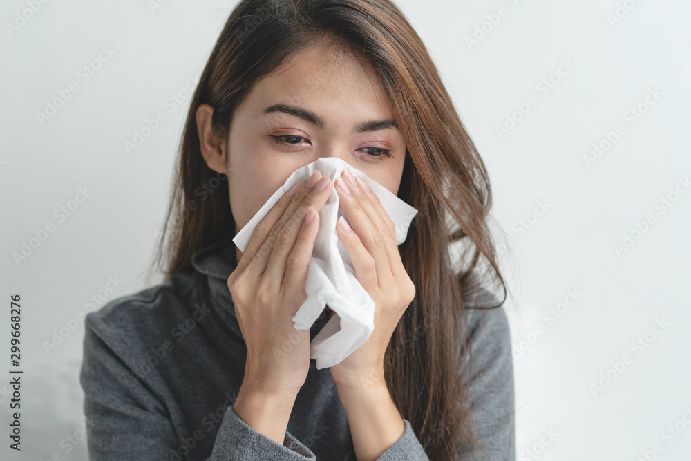 close up young girl using tissue paper stop runny nose symptom on the bed at home. close up young girl using tissue paper stop runny nose symptom on the bed at home.