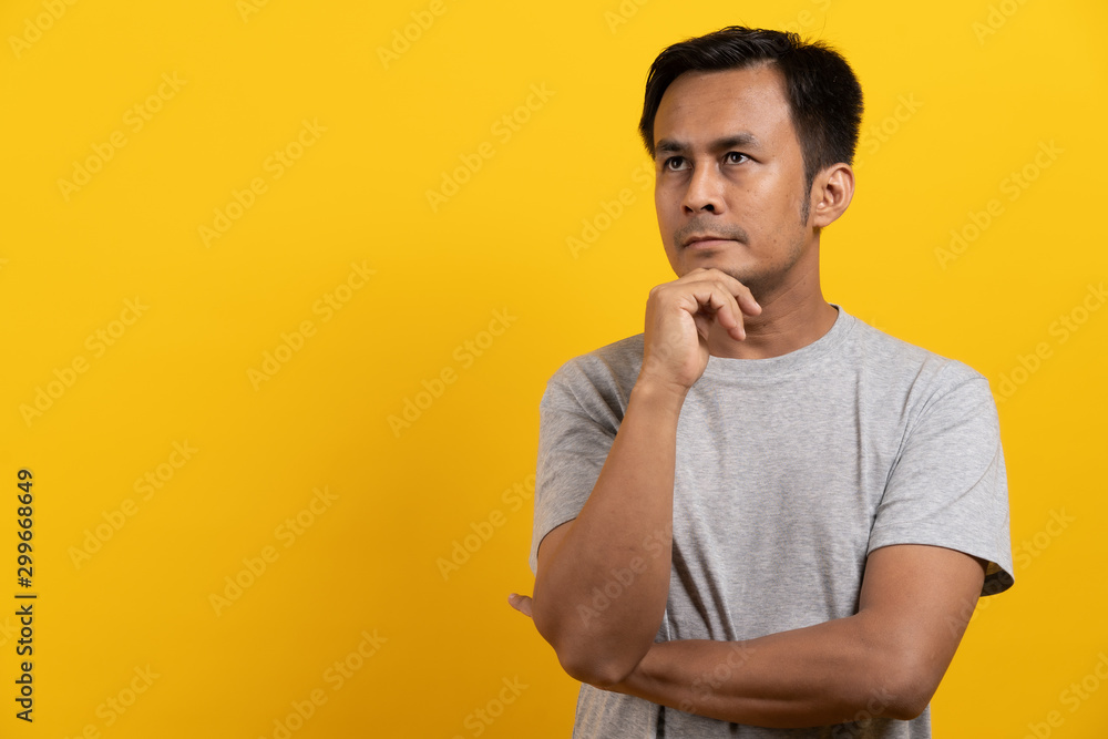 Cute asian man in casual thinking and imagination isolated on yellow background Cute asian man in casual thinking and imagination isolated on yellow background