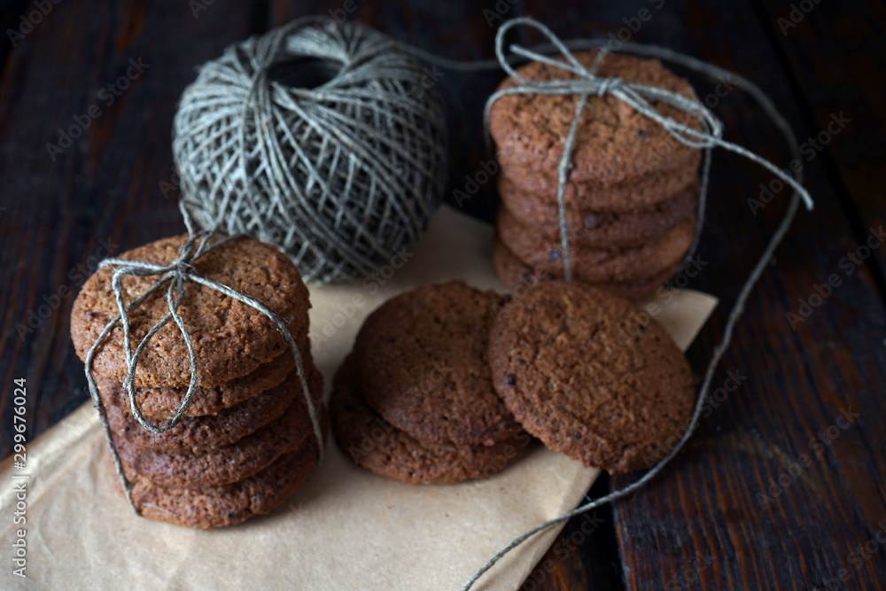 Stacks of homemade oatmeal cookies tied with twine on a dark wooden table