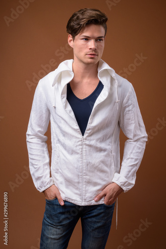 Studio shot of young handsome man against brown background © Ranta Images