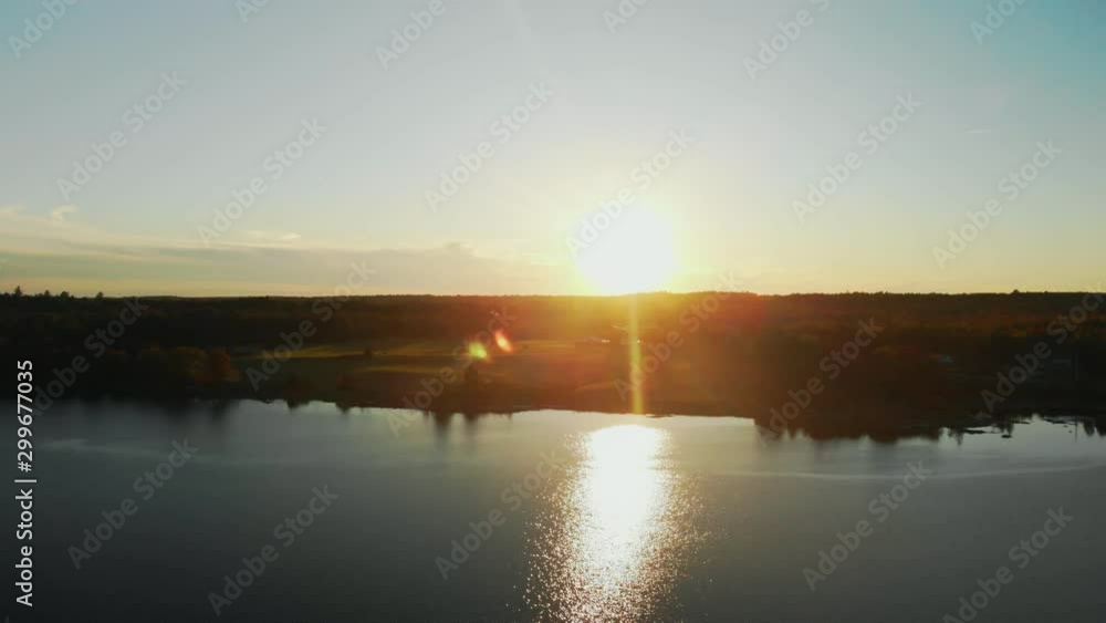 Rotating aerial pan of a sunset over a lake with tree silhouettes in the foreground and the sun reflecting beautifully on the water Rotating aerial pan of a sunset over a lake with tree silhouettes in the foreground and the sun reflecting beautifully on the water
