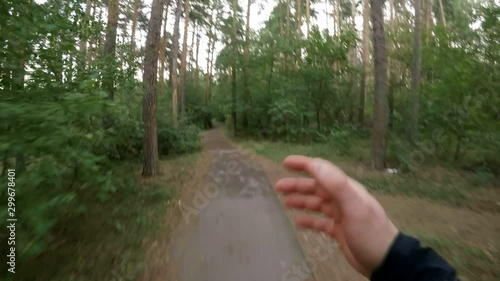 Point of view shot of sportsman running on path in forest while training outdoors on summer day photo