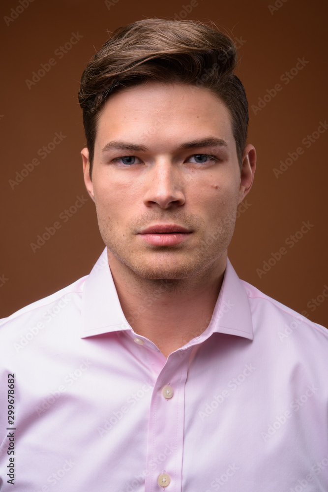 Studio shot of young handsome businessman with pink shirt