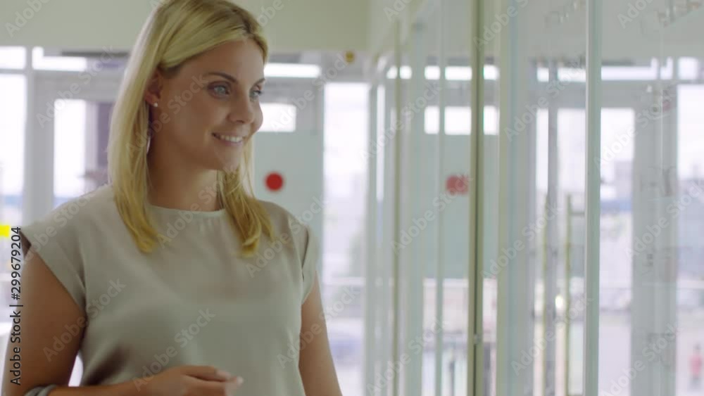 Tilt up shot of cheerful blond woman walking into optical store and looking at eyeglasses frames on display Tilt up shot of cheerful blond woman walking into optical store and looking at eyeglasses frames on display