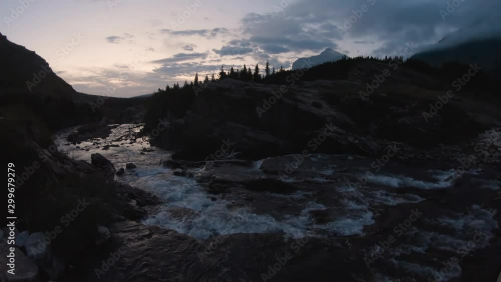 Beautiful View of the Glacier River during a cloudy morning sunrise in the American Rockies. Taken in Swiftcurrent Lake, Glacier National Park, Montana, United States. Beautiful View of the Glacier River during a cloudy morning sunrise in the American Rockies. Taken in Swiftcurrent Lake, Glacier National Park, Montana, United States.