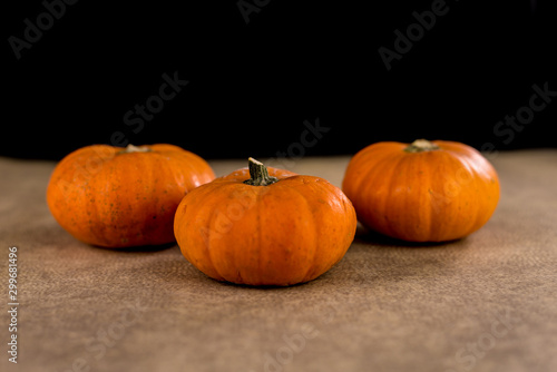 Small seasonal orange pumpkins with textured background