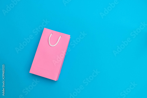 Shopping sale concept. Pink paper bag on blue background. Top view with copy space