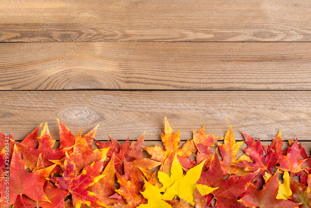 Obraz premium Background texture with old wooden table and yellow autumnal fallen maple leaves Top view Flat lay copy space Place for text Hello autumn, september, october, november, nature concept Rustic style