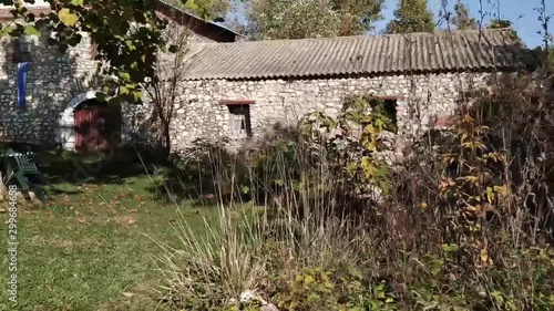 Paning shot from a stone wall revealing an old house made of stones close to a rolling creek in Kefalari in Drama, Greece photo