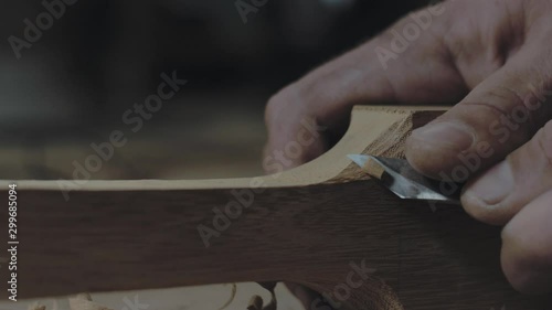 close-up of hands slicing a wooden product with a knife. a carpenter processes a wooden beam with a knife. 4k video. 59.94 fps