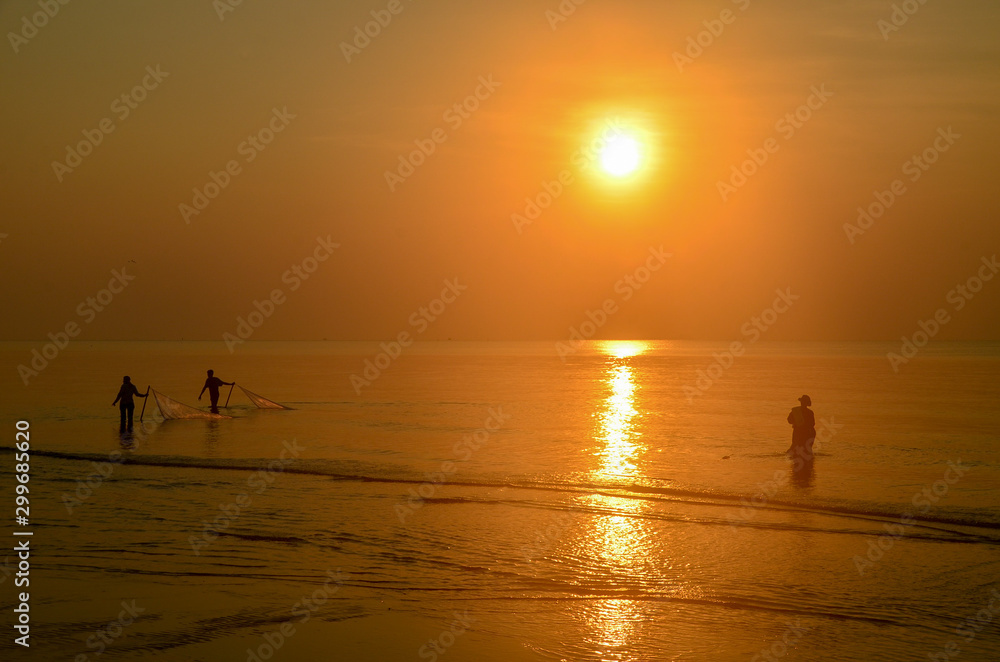 Tropical sunrise seascape with sun water reflection and fishermen silhouettes, Thailand. Tropical sunrise seascape with sun water reflection and fishermen silhouettes, Thailand.