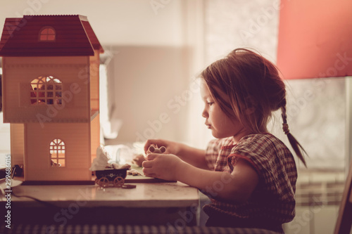 Girl child with pigtail plays with dollhouse photo