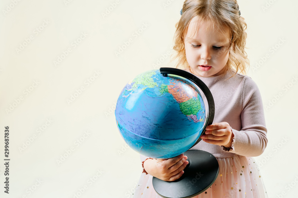 concept of travel, tourism. Girl on an isolated background holds a globe, a suitcase is standing nearby concept of travel, tourism. Girl on an isolated background holds a globe, a suitcase is standing nearby