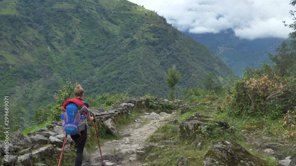 Woman walks through path, hills valley in Nepal mountain range Woman walks through path, hills valley in Nepal mountain range
