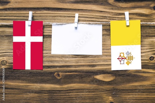 Canvas Print Hanging flags of Denmark and Vatican City attached to rope with clothes pins with copy space on white note paper on wooden background
