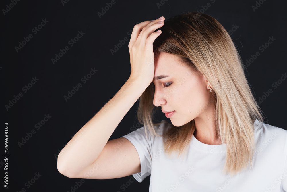 Emotional portrait of a girl holding her head in her hands, feeling pain.