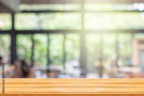 Empty wooden table with abstract blurry image of coffee shop or cafe restaurant in background for product showing and advertising. © Angkana