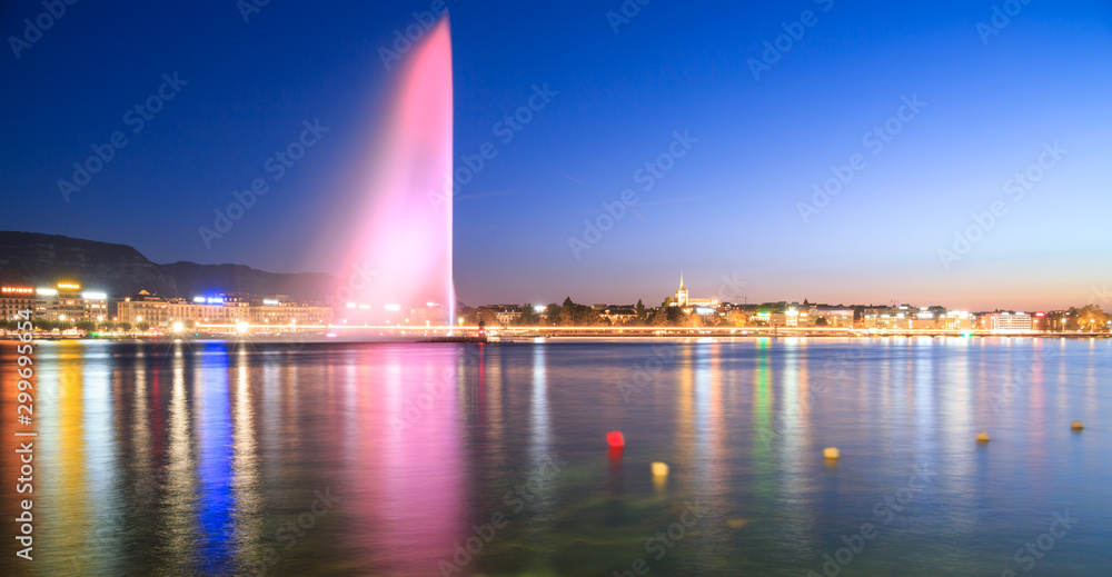 Geneva city lights at night . Pink fountain is reflected in still lake in the evening. Colorful long exposure and blurred buoys on the surface.