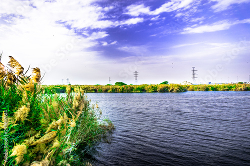 breathtaking view of a lake and clouds on the sky and heavy transmission electricity supply line in the background 