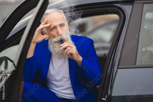 Old stylish man in the luxury car. Male with beard and mustash driving automobile. car sales salon. photo