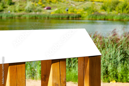 Blank horizontal information sign in park in front of a lake on wooden stand